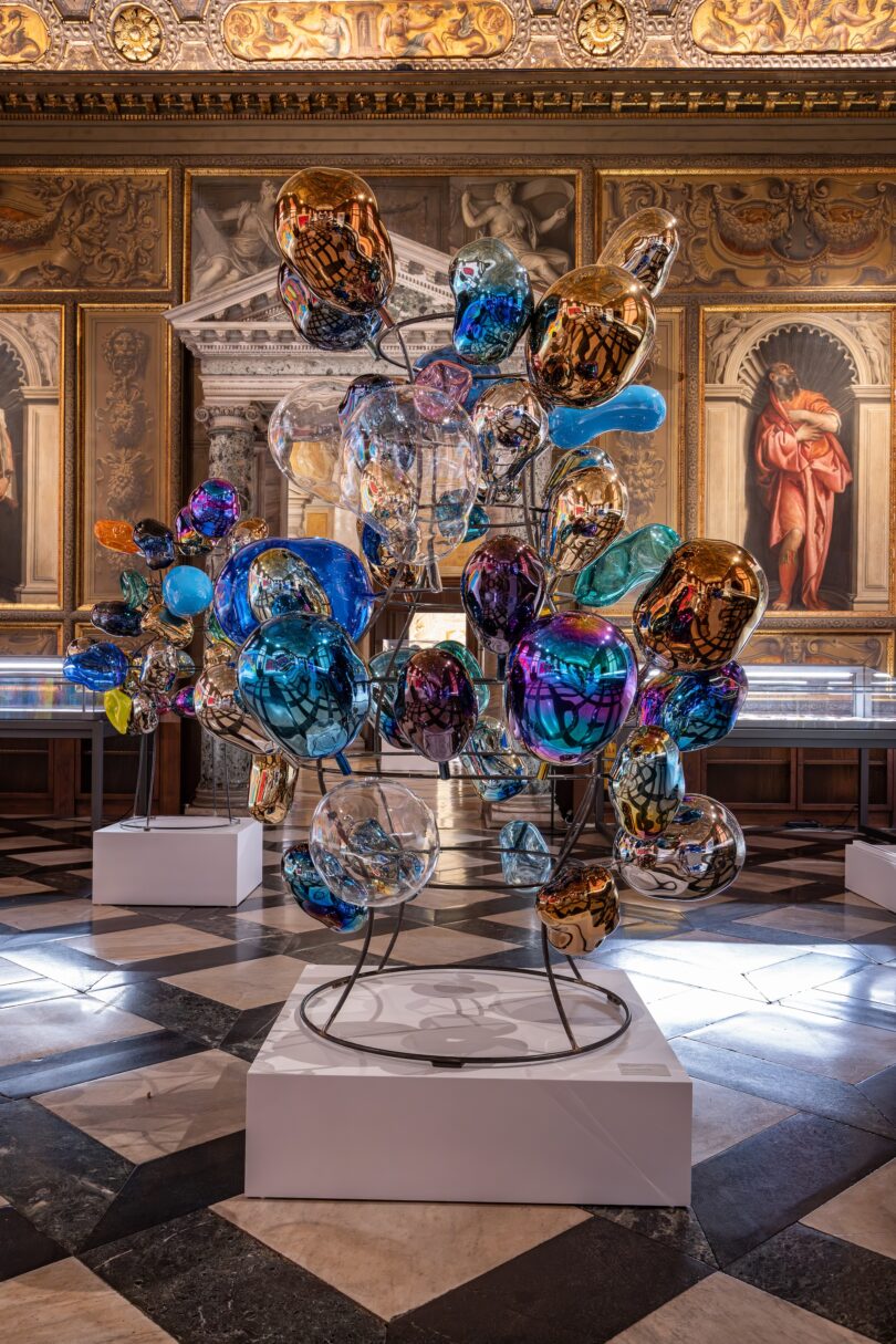 Installationsansicht mit Dokoupils auf Flaschentrocknern aufgespießten Ballons in der Biblioteca Marciana